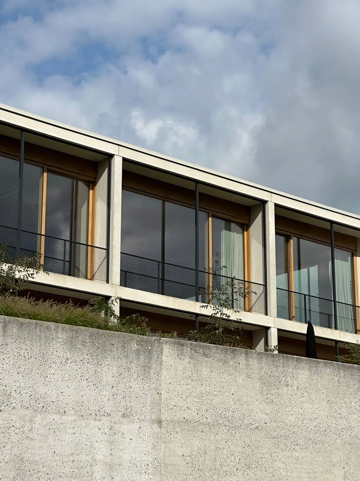 Avant : façade vitrée d'hôtel sans film — les chambres et les rideaux sont visibles depuis l'extérieur en journée