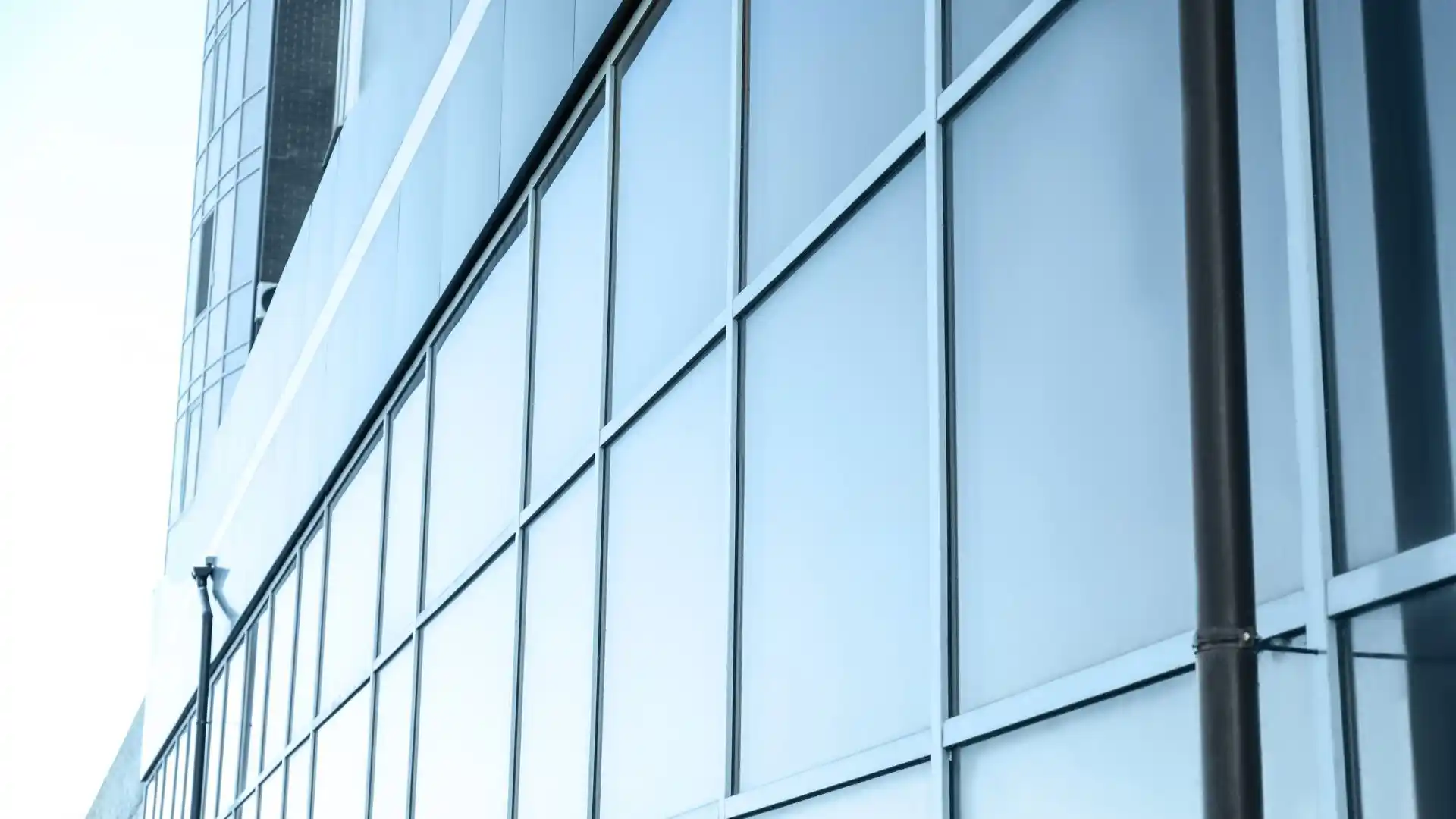 Façade vitrée d'immeuble de bureaux protégée par un film solaire, rejet de la chaleur sur mur-rideau