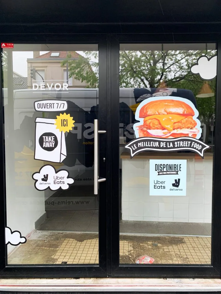 Porte vitrée de restaurant à emporter avec stickers de vitrophanie (horaires, plats, livraison)